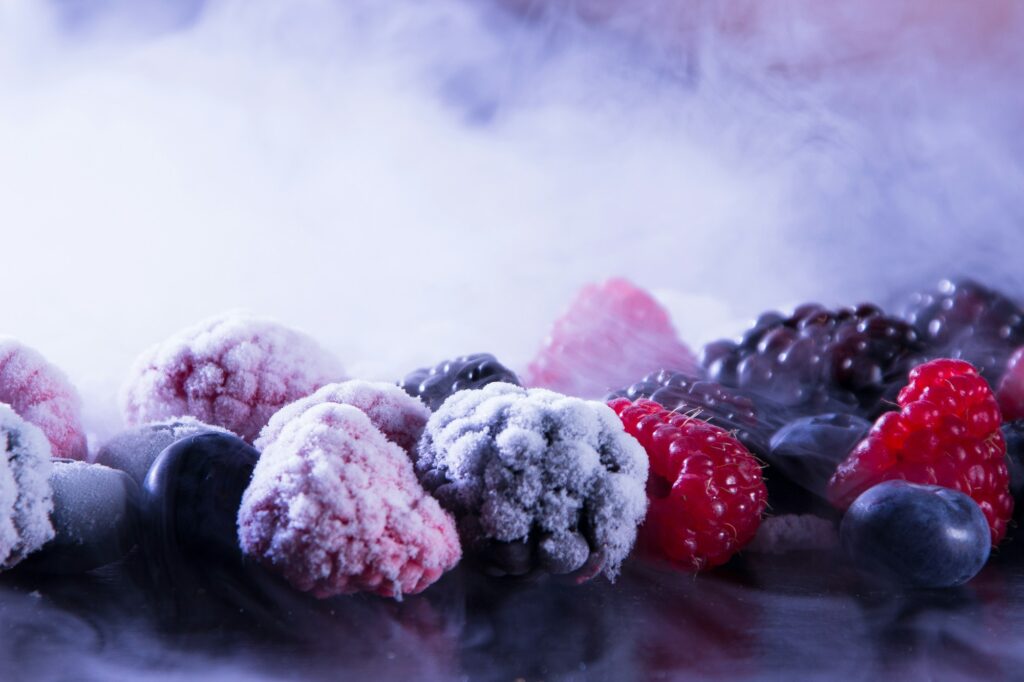 Frosted raspberries, blackberries and blueberries straight from the freezer, with cold mist around them