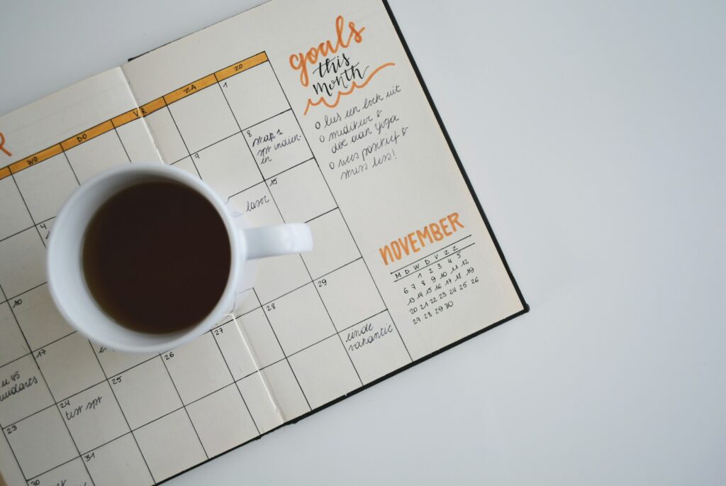 A cup of black coffee resting on an open monthly planner with handwritten goals for November
